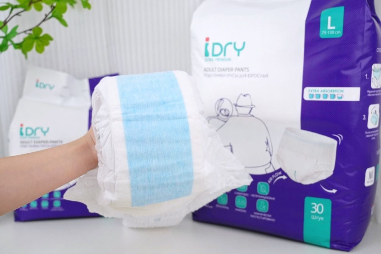 Подгузники-трусы для взрослых iDry: изделие в руке на фоне упаковок