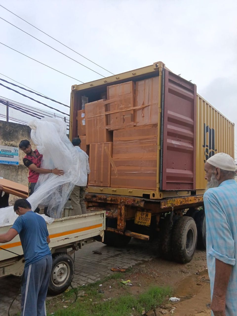 Погрузка: коробки перегружают из грузовика в контейнер, рабочие укладывают груз